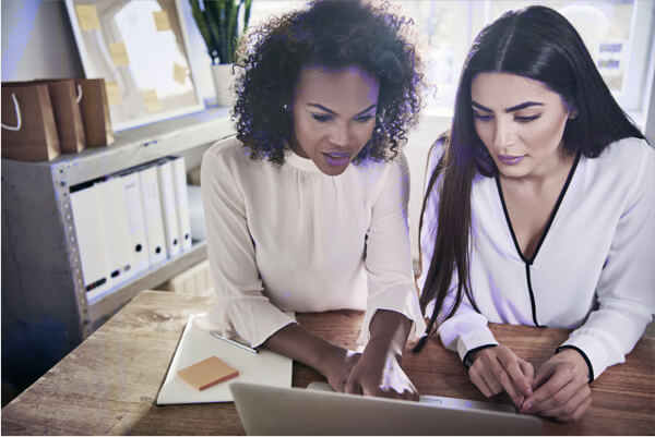 Two women at a desk looking at a laptop