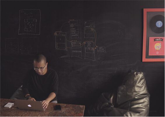 Man sitting using a laptop with a chalkboard background
